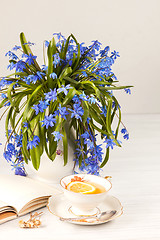 Image showing Tea with  lemon and bouquet of  blue primroses on the table