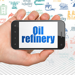 Image showing Manufacuring concept: Hand Holding Smartphone with Oil Refinery on display