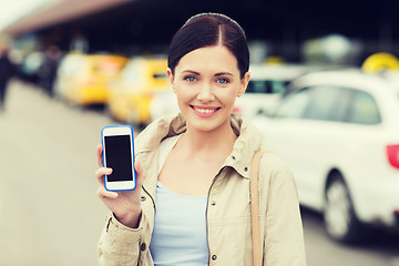 Image showing smiling woman showing smartphone over taxi in city