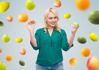 Image showing smiling woman choosing between apple and cookie