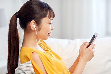 Image showing happy asian woman with smartphone and earphones