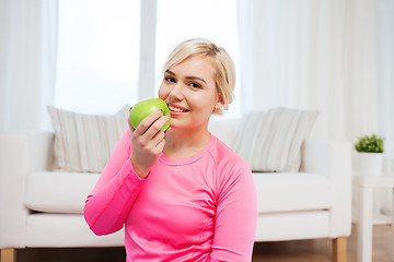 Image showing happy woman eating apple at home