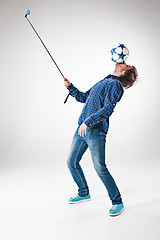 Image showing The portrait of man with ball, holding selfie stick on white background