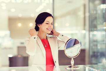 Image showing happy woman choosing pendant at jewelry store