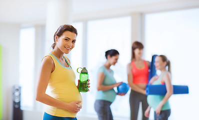 Image showing happy pregnant woman with water bottle in gym