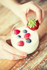 Image showing close up of woman hands with yogurt and berries