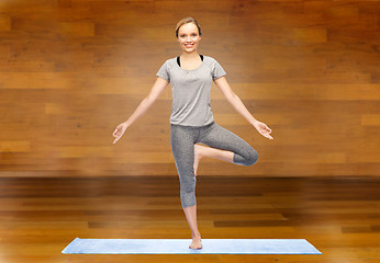 Image showing woman making yoga in tree pose on mat