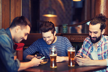 Image showing male friends with smartphones drinking beer at bar