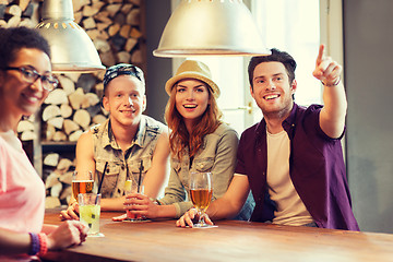 Image showing happy friends with drinks pointing finger at bar