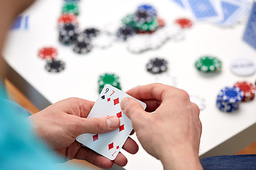 Image showing close up of male hand with playing cards and chips