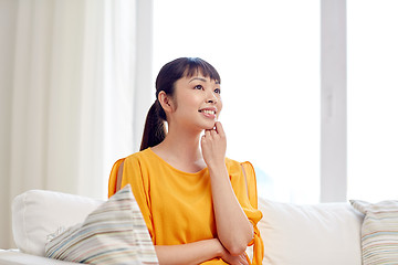 Image showing happy asian young dreaming woman at home