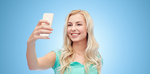 Image showing smiling young woman taking selfie with smartphone