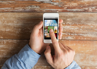 Image showing close up of male hands with smartphone on table