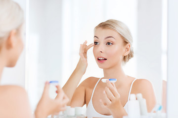 Image showing young woman putting on contact lenses at bathroom