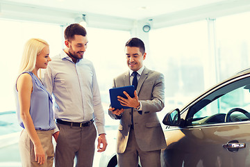 Image showing happy couple with car dealer in auto show or salon