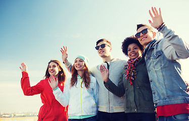 Image showing happy teenage friends in shades waving hands