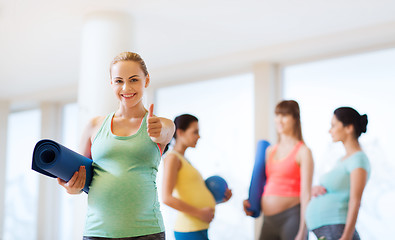 Image showing pregnant woman with mat in gym showing thumbs up 