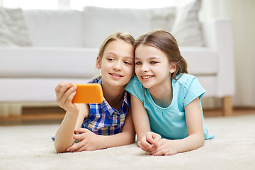 Image showing happy girls with smartphone taking selfie at home