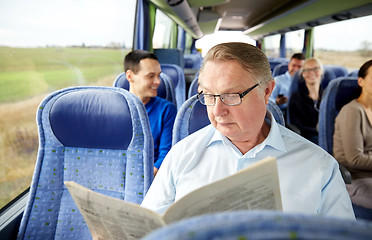 Image showing happy senior man reading newspaper in travel bus