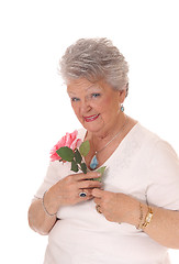 Image showing Senior woman holding pink rose.