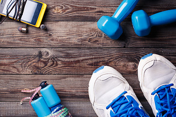 Image showing Sports equipment - sneakers, skipping rope, dumbbells, smartphone and headphones. 