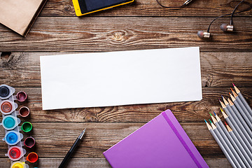 Image showing Watercolors, color pencils and sketchbook on wooden table. Flat lay photo with empty space for logo, text.