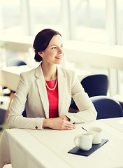 Image showing happy woman sitting at table in restaurant