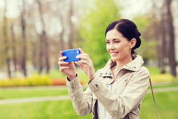 Image showing smiling woman taking picture with smartphone