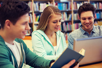 Image showing happy students with laptop and book at library