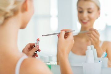 Image showing woman with lipstick and make up brush at bathroom