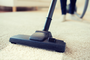 Image showing close up of woman legs with vacuum cleaner at home