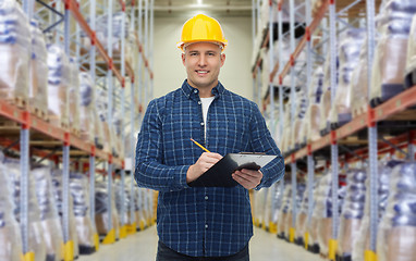 Image showing happy man in helmet with clipboard at warehouse