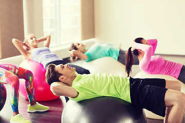 Image showing happy people flexing abdominal muscles on fitball