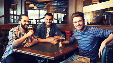 Image showing happy male friends drinking beer at bar or pub