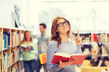 Image showing happy student girl or woman with book in library