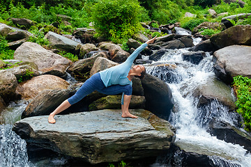 Image showing Woman practices yoga asana Utthita Parsvakonasana outdoors