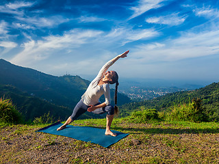 Image showing Woman practices yoga asana Utthita Parsvakonasana outdoors