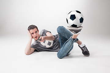 Image showing The portrait of fan with ball, holding  tv remote on white background