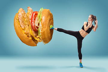 Image showing Fit, young, energetic woman boxing hamburger as unhealthy food