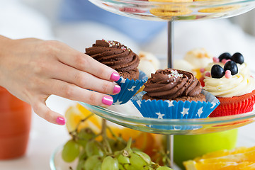 Image showing close up of hand taking cupcake from cake stand