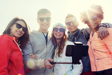 Image showing friends taking selfie with smartphone on stick