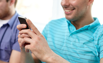 Image showing close up of happy friends with smartphones at home