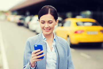 Image showing smiling woman with smartphone over taxi in city