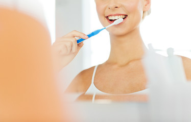 Image showing woman with toothbrush cleaning teeth at bathroom