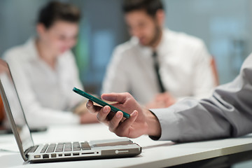 Image showing close up of  businessman hands  using smart phone on meeting