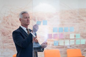 Image showing senior business man making plans with sticker