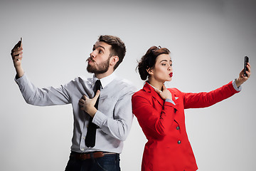 Image showing Business concept. The two young colleagues holding mobile phones on gray background