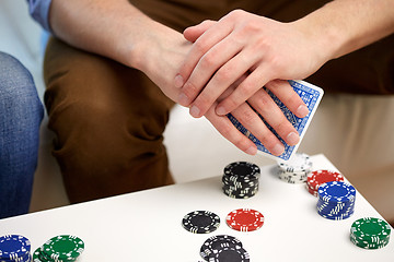 Image showing close up of male hand with playing cards and chips