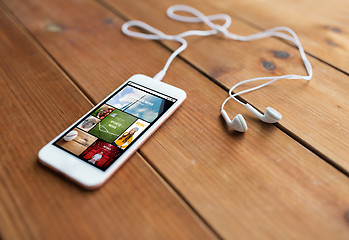 Image showing close up of smartphone and earphones on wood