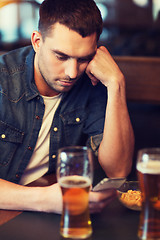 Image showing man with smartphone drinking beer at bar